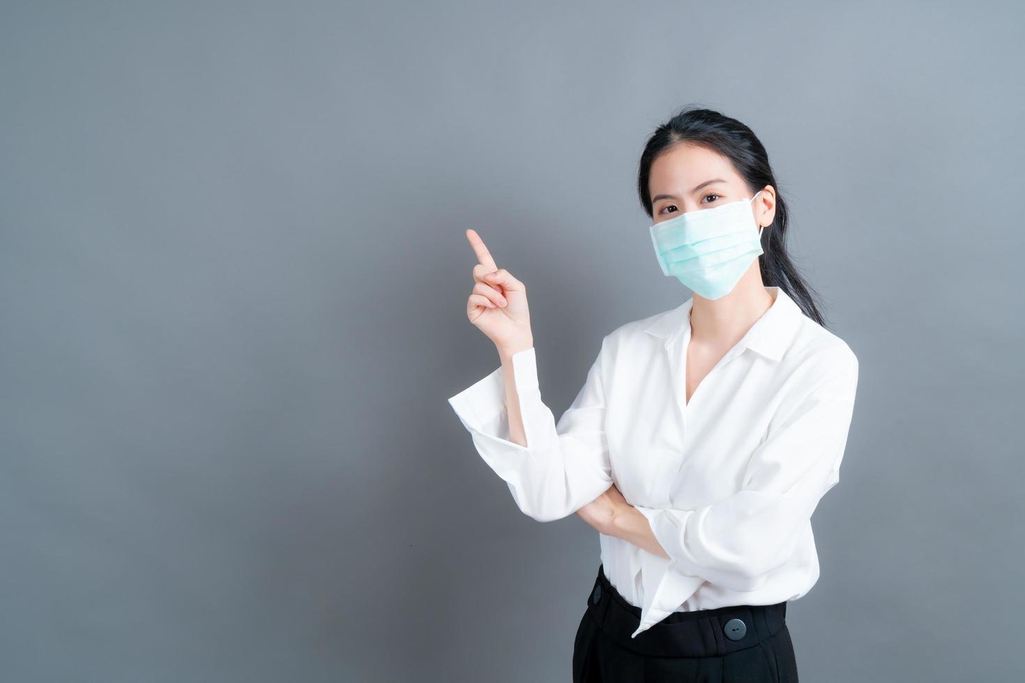 Young Asian woman wearing medical face mask and finger pointing photo