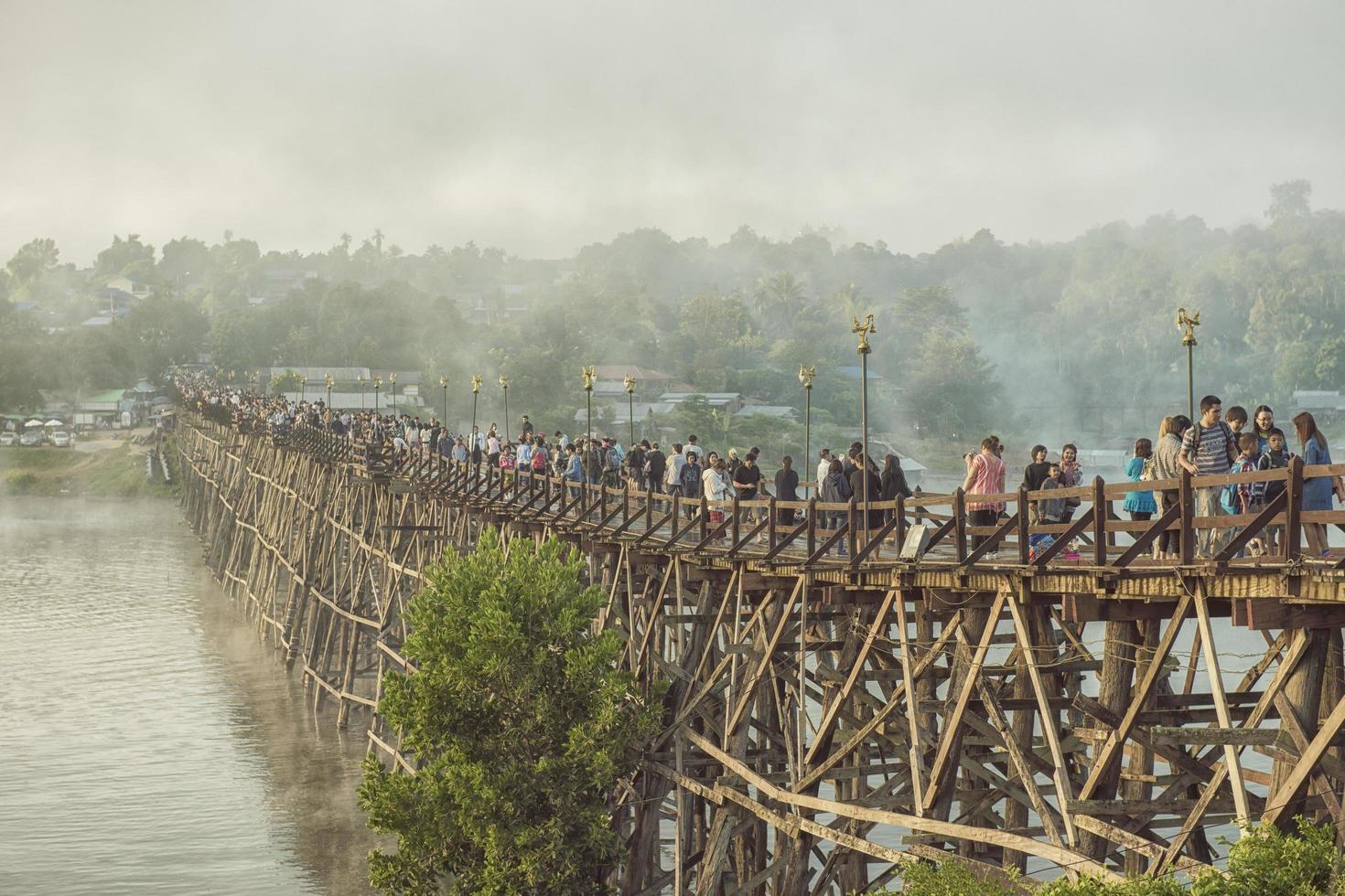 Tourists walk on the wooden bridge over the river in Kanchanaburi, Thailand 2018 photo