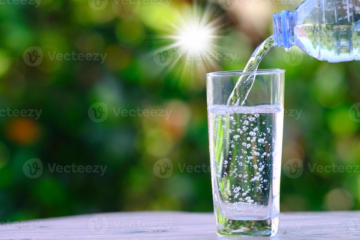 Verter agua potable purificada de la botella sobre la mesa de madera y el concepto de salud de agua mineral foto