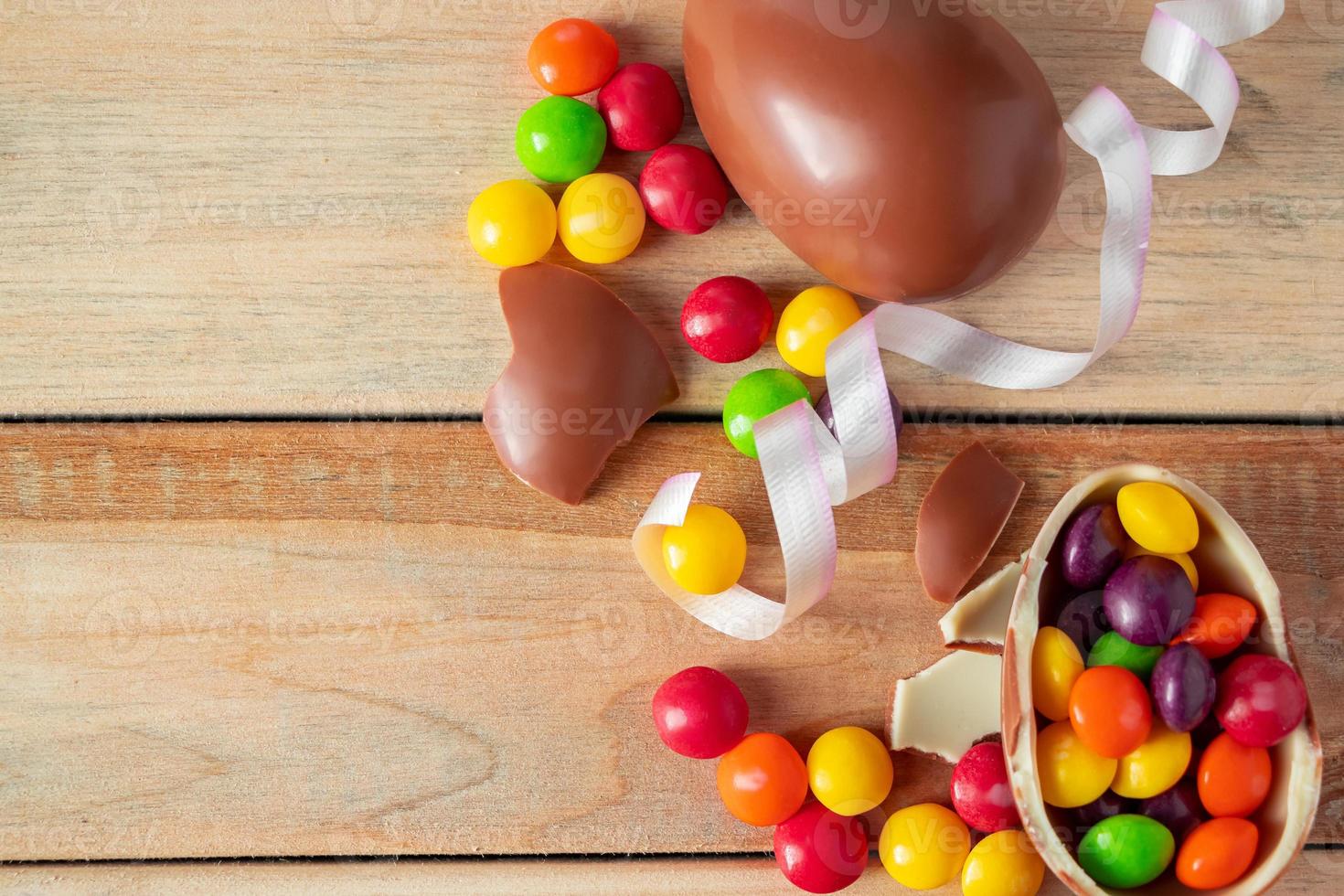 dulces multicolores y huevos de chocolate de pascua sobre un fondo de madera clara. foto