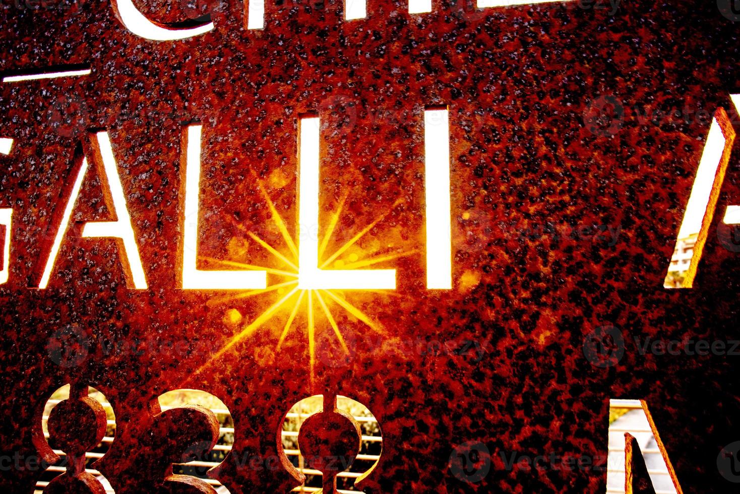 Sunset through the letters on a metal sign photo