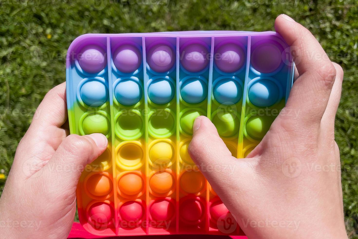 colorful anti-stress sensory fidget push pop it toy in children's hands photo