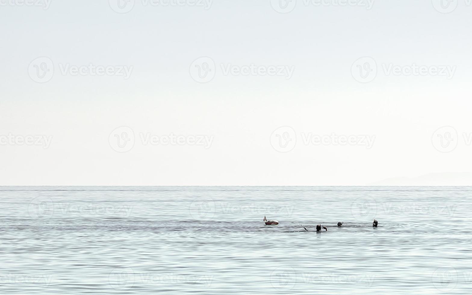 Three scuba divers talking each other with hand gesture signals. Three unrecognizable people on the sea diving together. photo