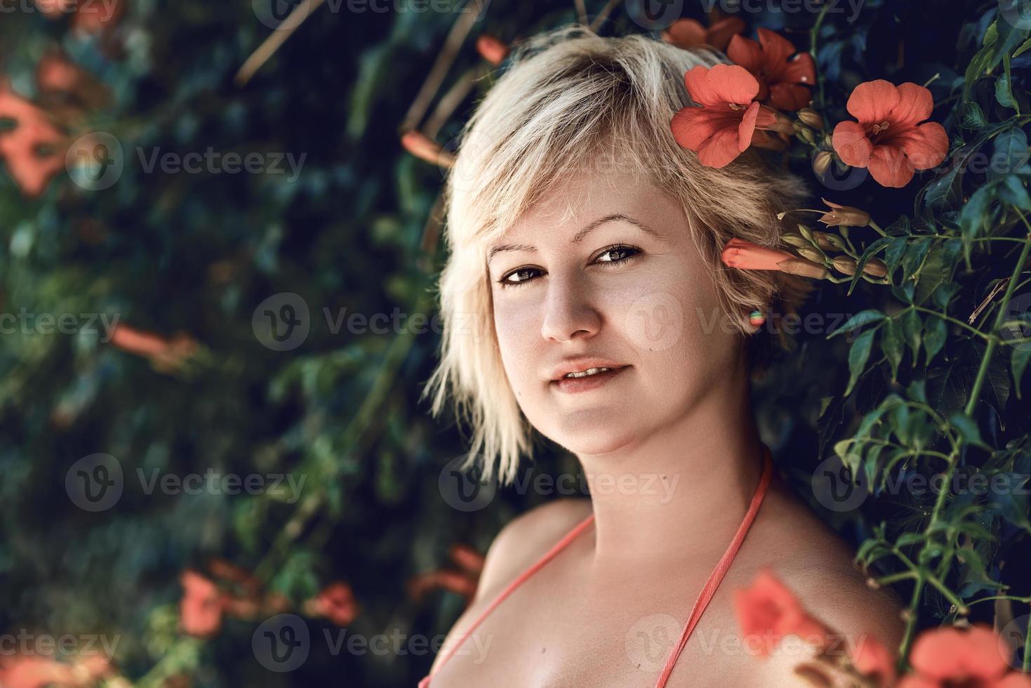 Beautiful blonde woman portrait with the orange flowers of the trumpet vine bloom. Orange flowers of the trumpet vine or trumpet creeper, Campsis radicans, also known as cow itch vine. photo