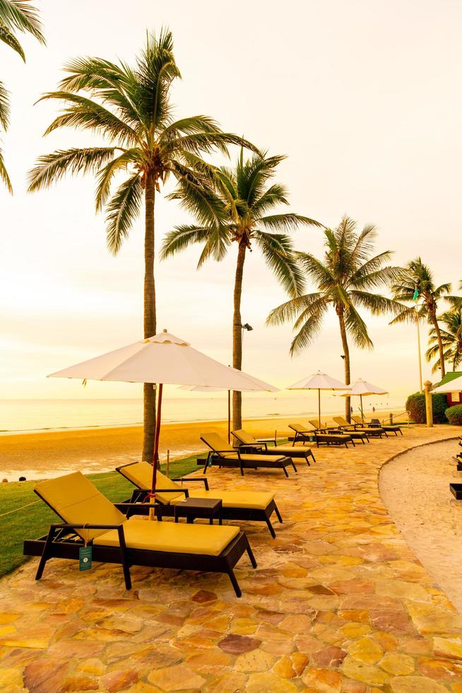 Umbrella and chair around swimming pool in hotel resort with sunrise in morning photo