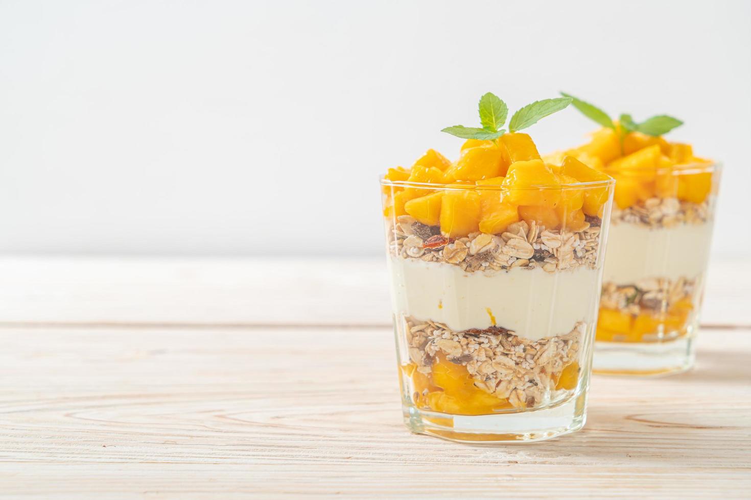 Yogur de mango fresco con granola en vidrio - estilo de comida saludable foto