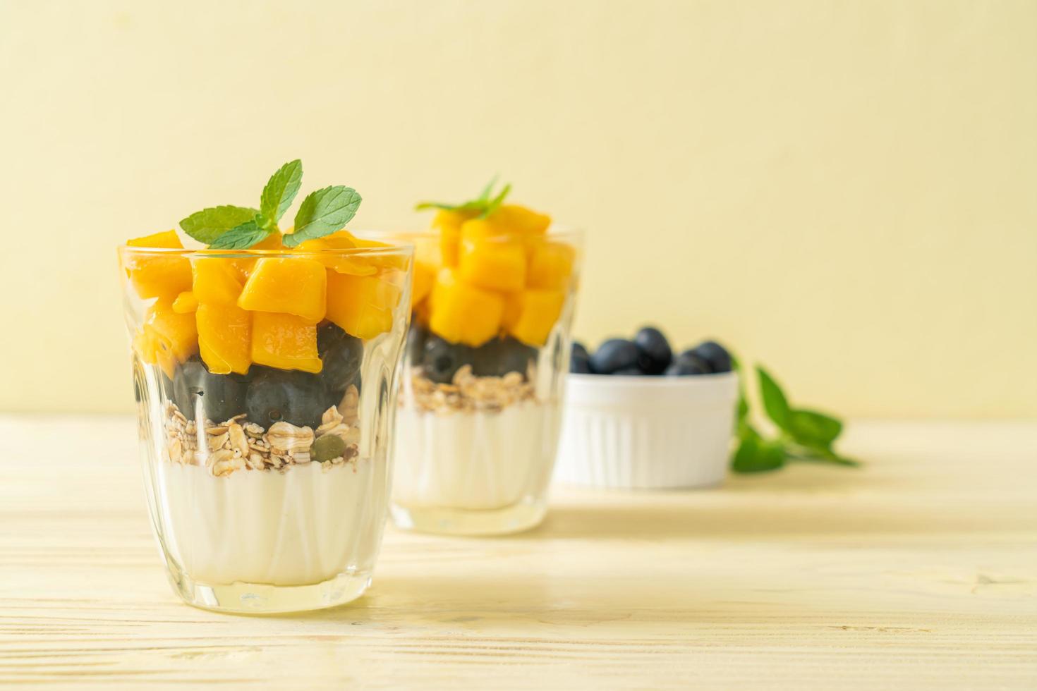 mango fresco casero y arándanos frescos con yogur y granola - estilo de comida saludable foto