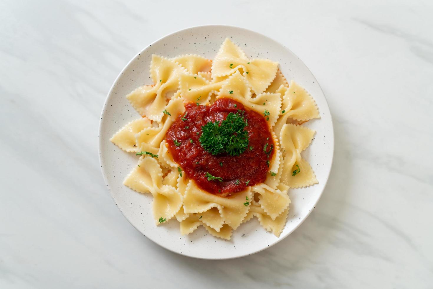 Pasta farfalle en salsa de tomate con perejil - estilo de comida italiana foto