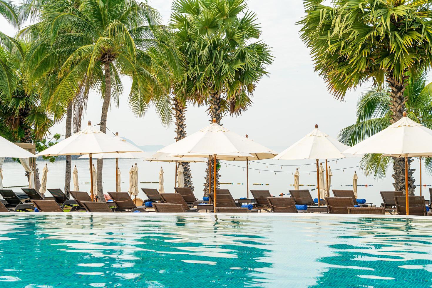 Empty beach chair with umbrella around swimming pool photo