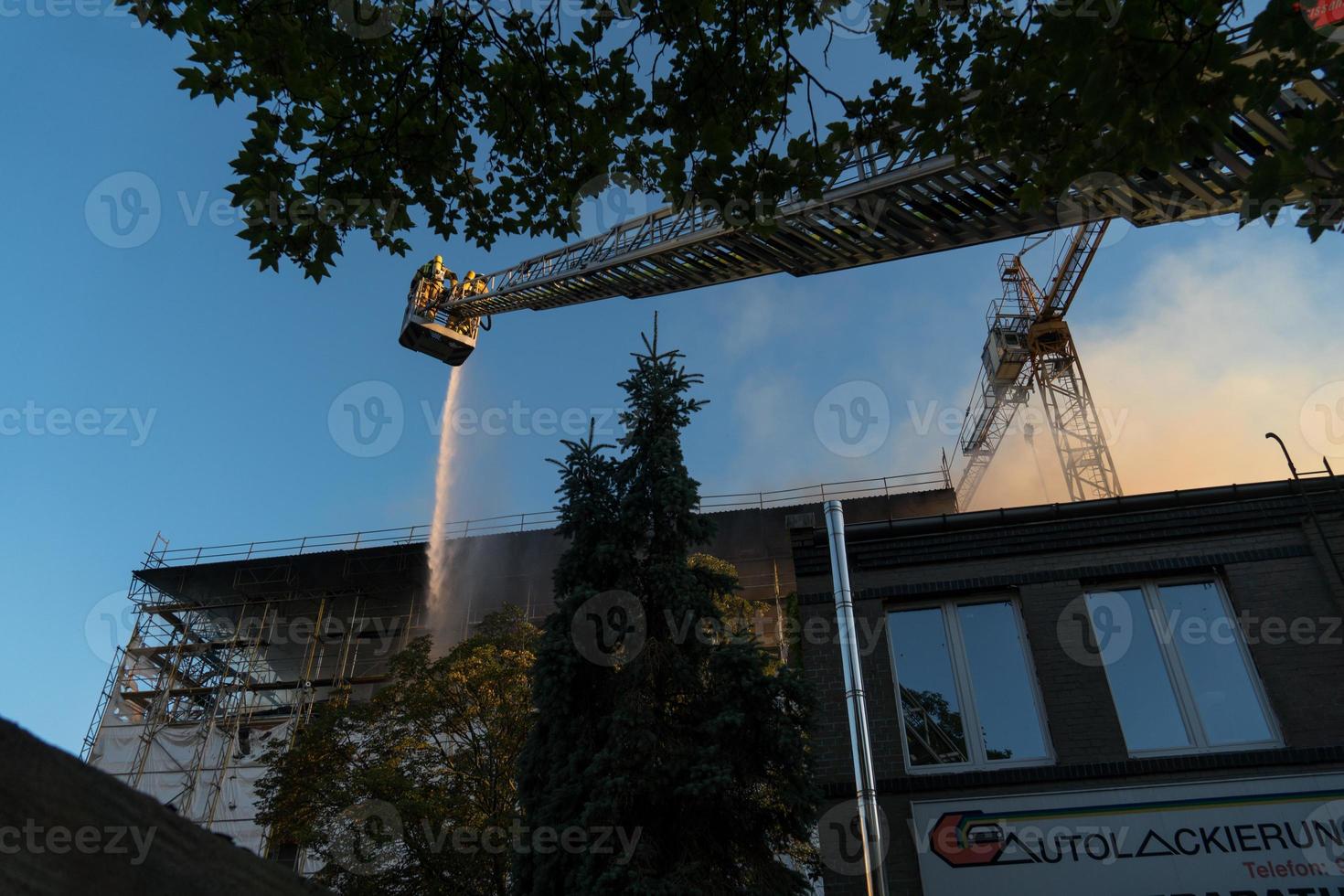 Firefighters climbing ladder against building and extinguishing a blaze photo