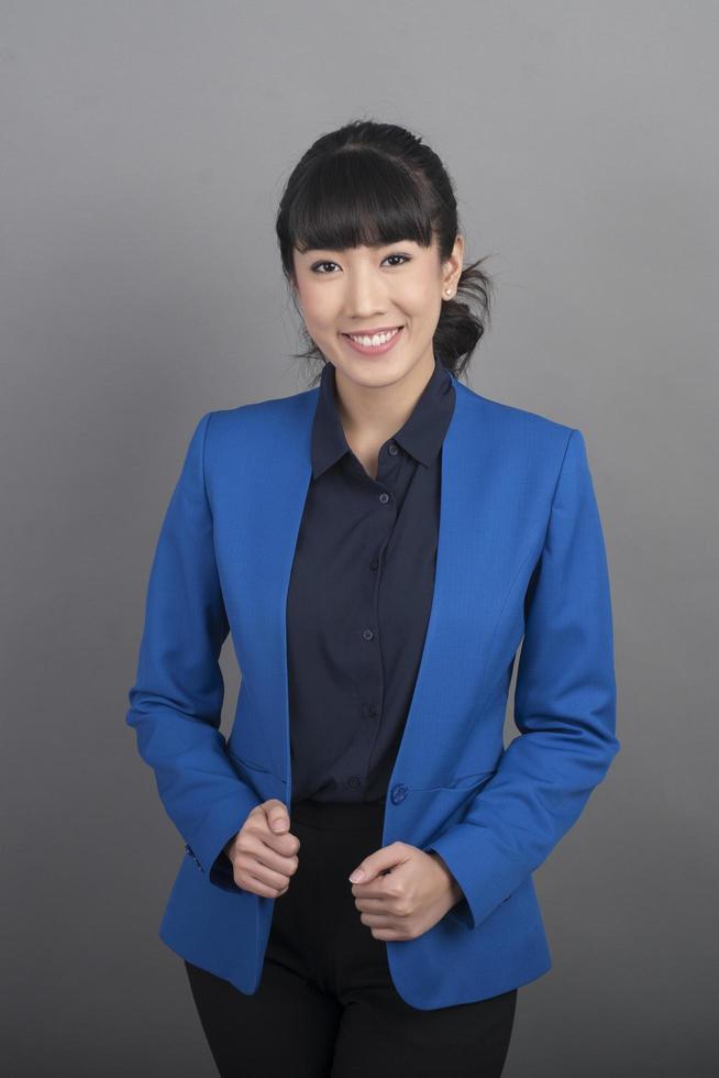 Sonriente mujer de negocios en blazer azul sobre fondo gris foto