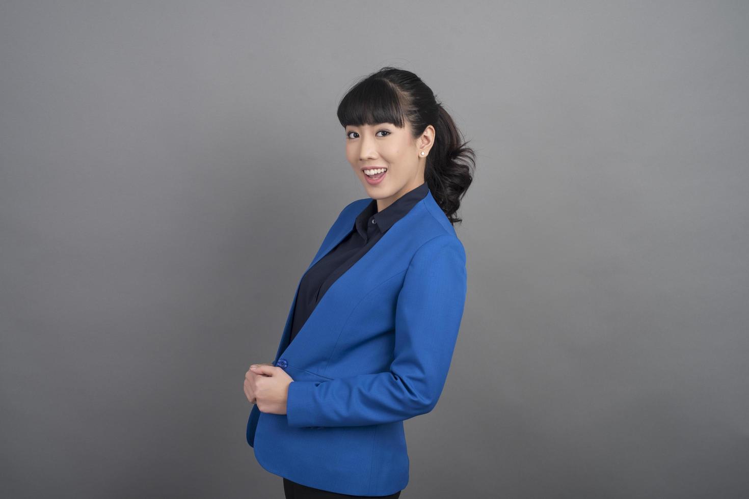 Smiling business woman in blue blazer on grey background photo