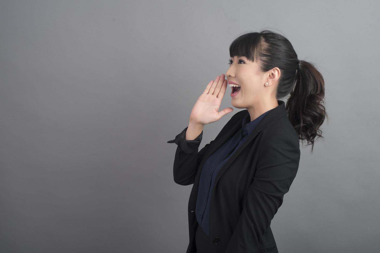 Smiling business woman in blazer on grey background photo