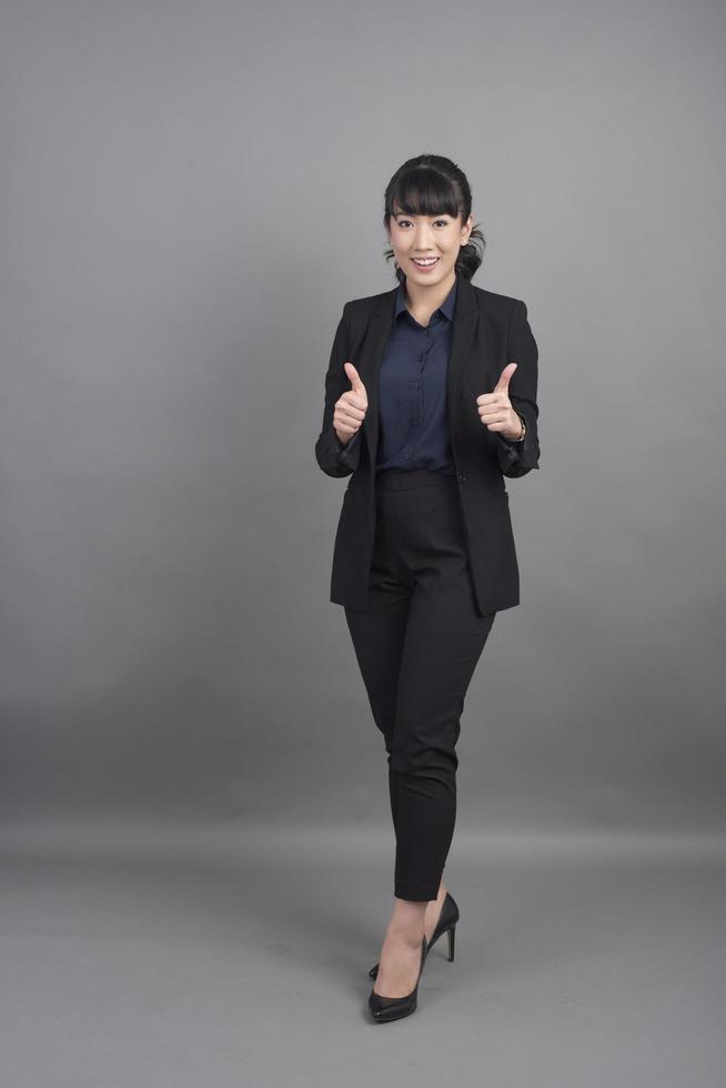 Smiling business woman in blazer on grey background photo