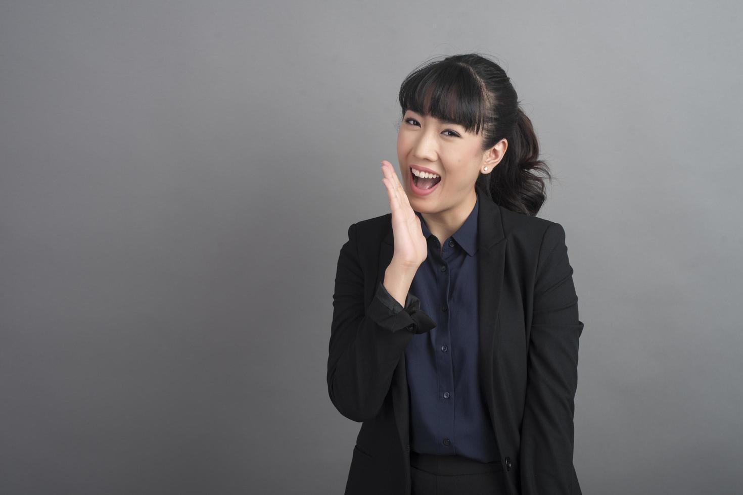 Smiling business woman in blazer on grey background photo