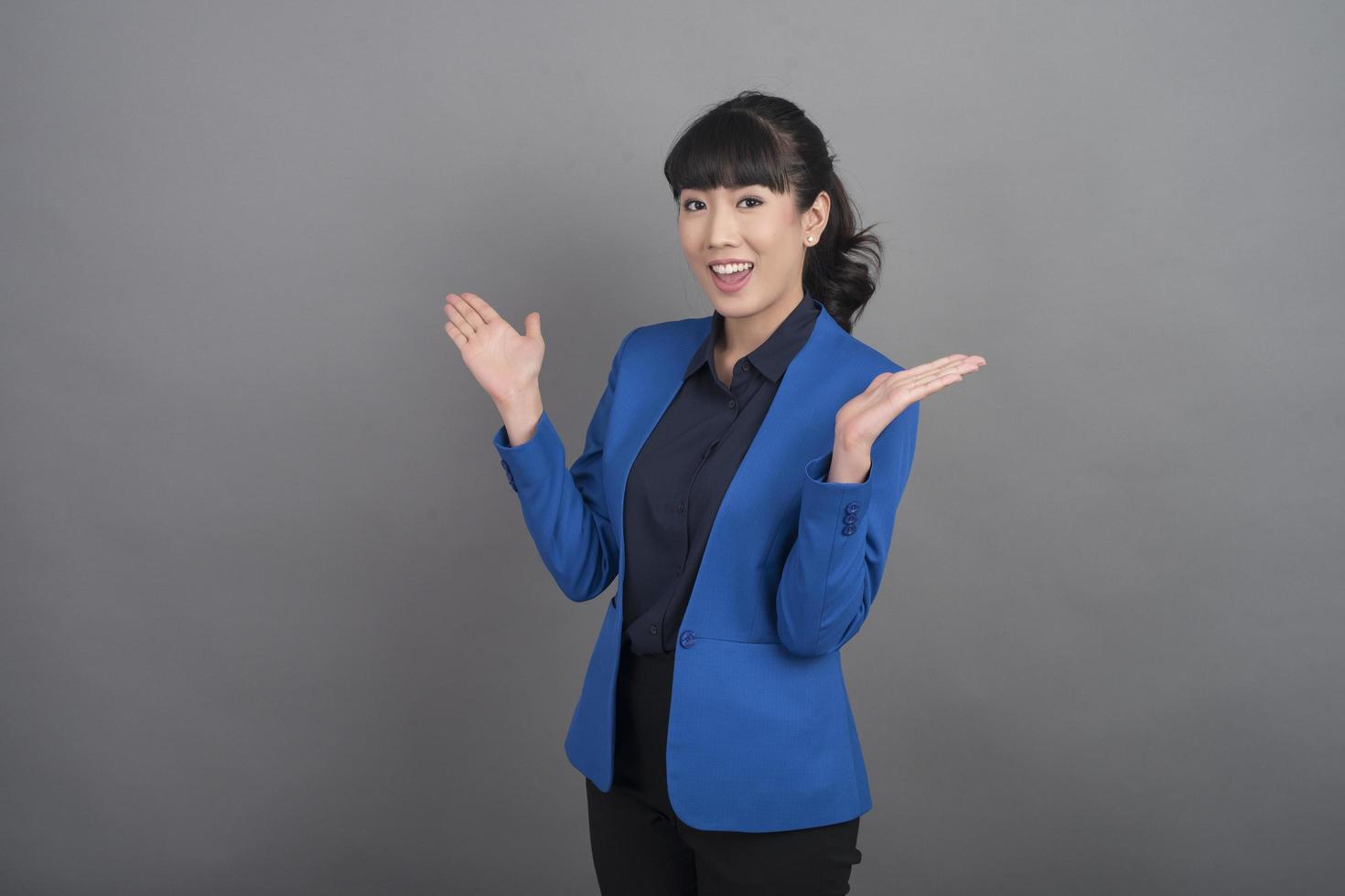 Sonriente mujer de negocios en blazer azul sobre fondo gris foto