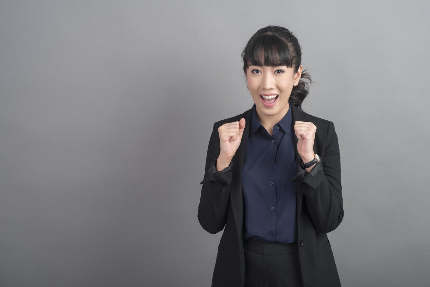 Smiling business woman in blazer on grey background photo