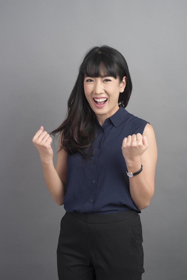 Smiling business woman in blazer on grey background photo