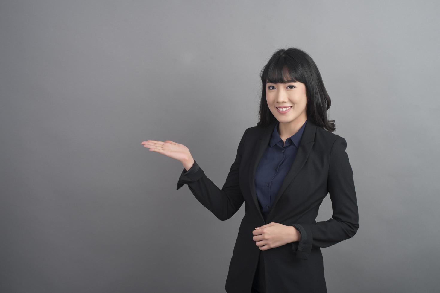 Smiling business woman in blazer on grey background photo