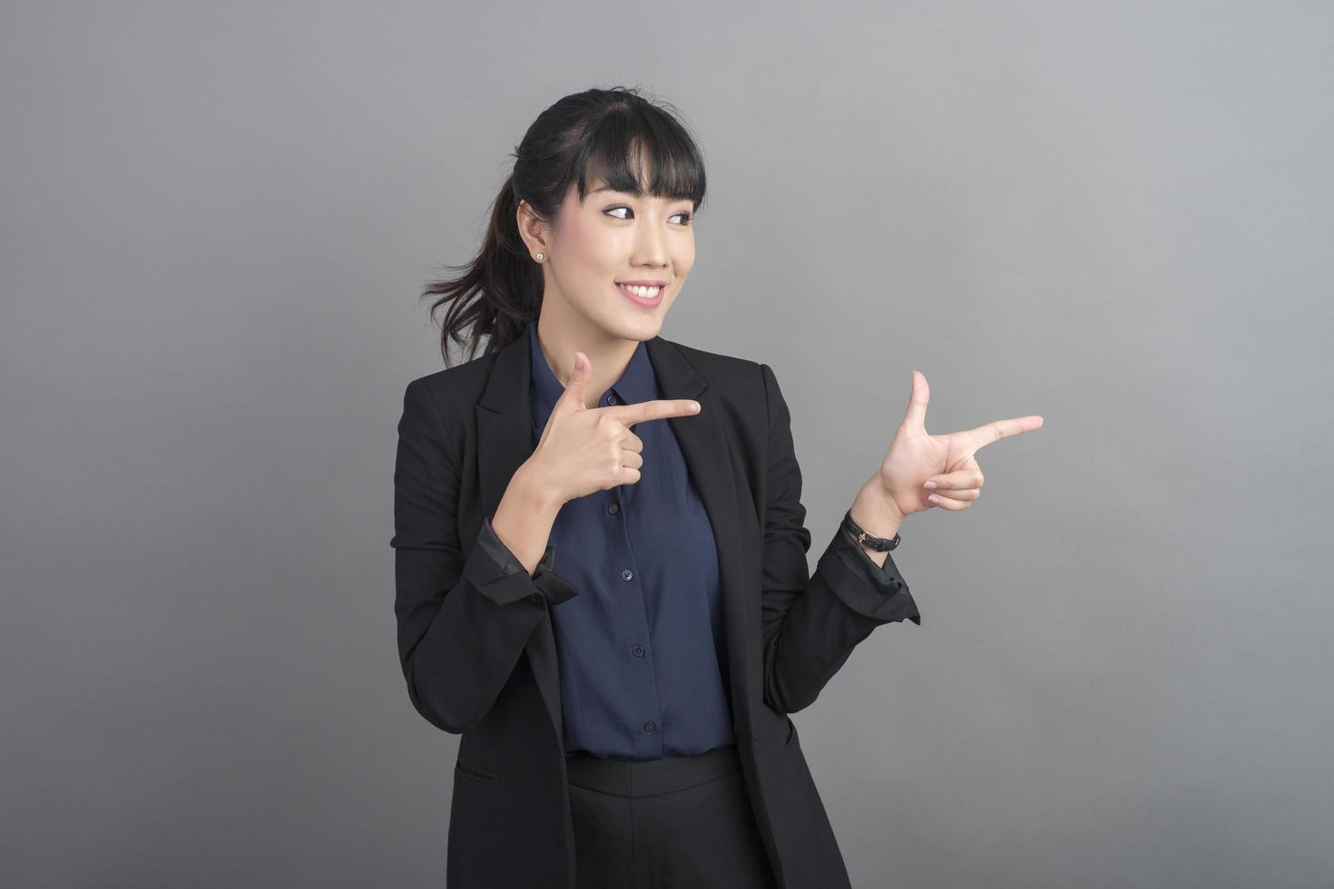 Smiling business woman in blazer on grey background photo