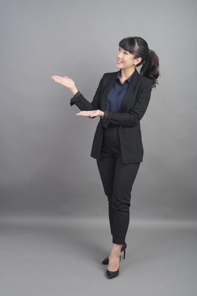 Smiling business woman in blazer on grey background photo