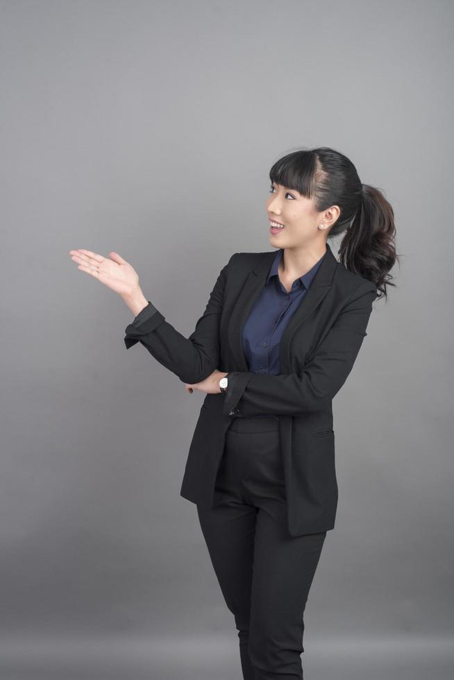 Smiling business woman in blazer on grey background photo