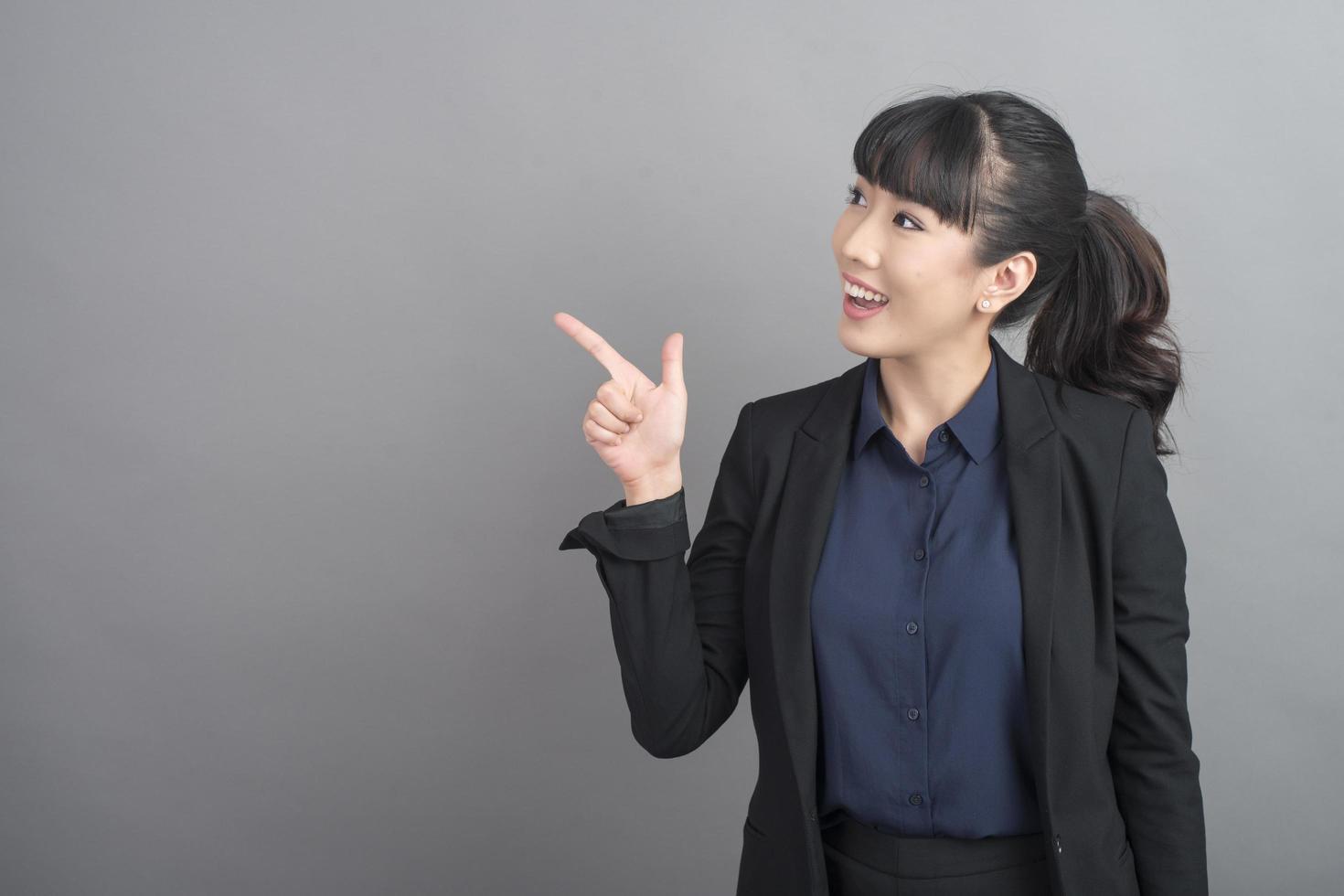 Smiling business woman in blazer on grey background photo