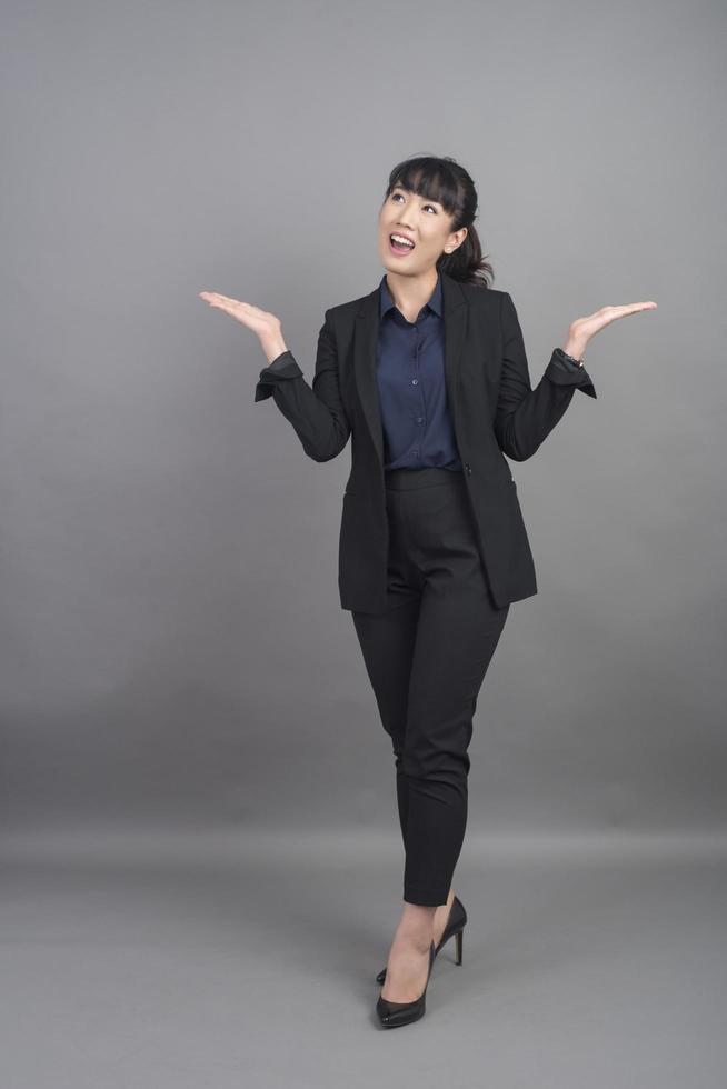 Sonriente mujer de negocios en blazer sobre fondo gris foto