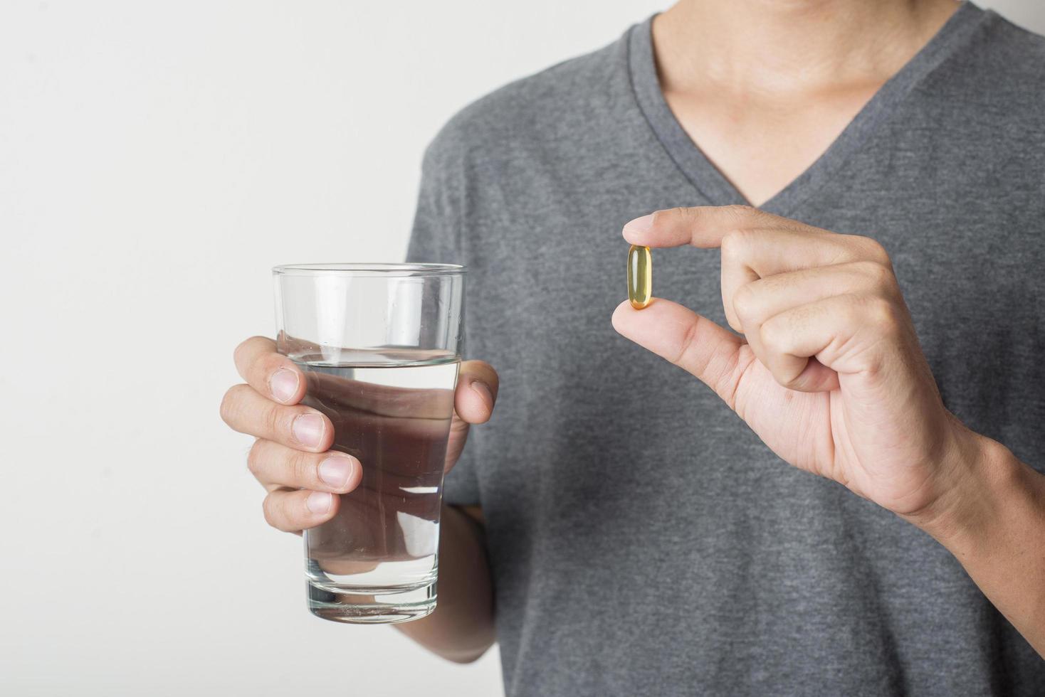 Man taking fish oil pill on white background photo