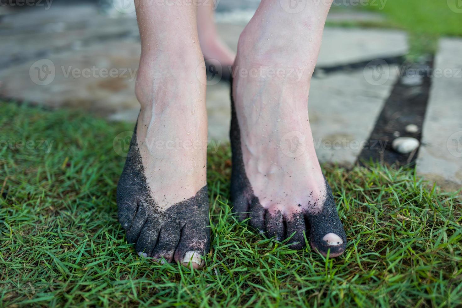 Feet at black sand beach in Bali photo