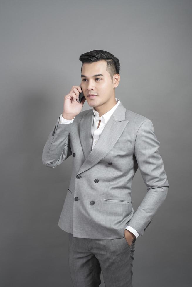 Businessman is talk with cell phone about business contact, portrait in studio grey background photo