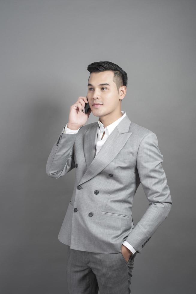 Businessman is talk with cell phone about business contact, portrait in studio grey background photo