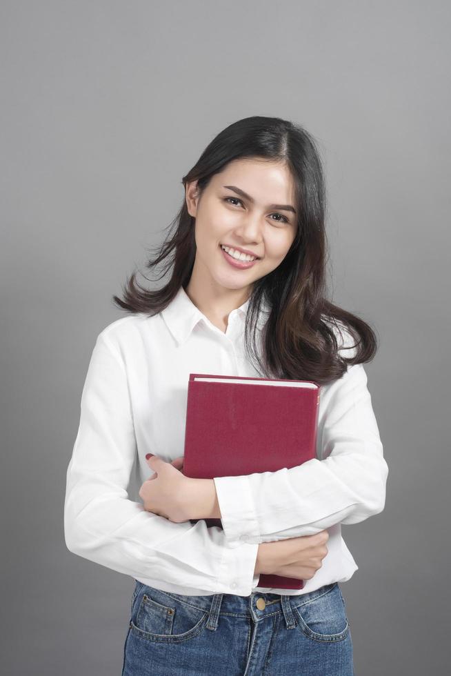 Portrait of woman University student holding book in studio grey background photo