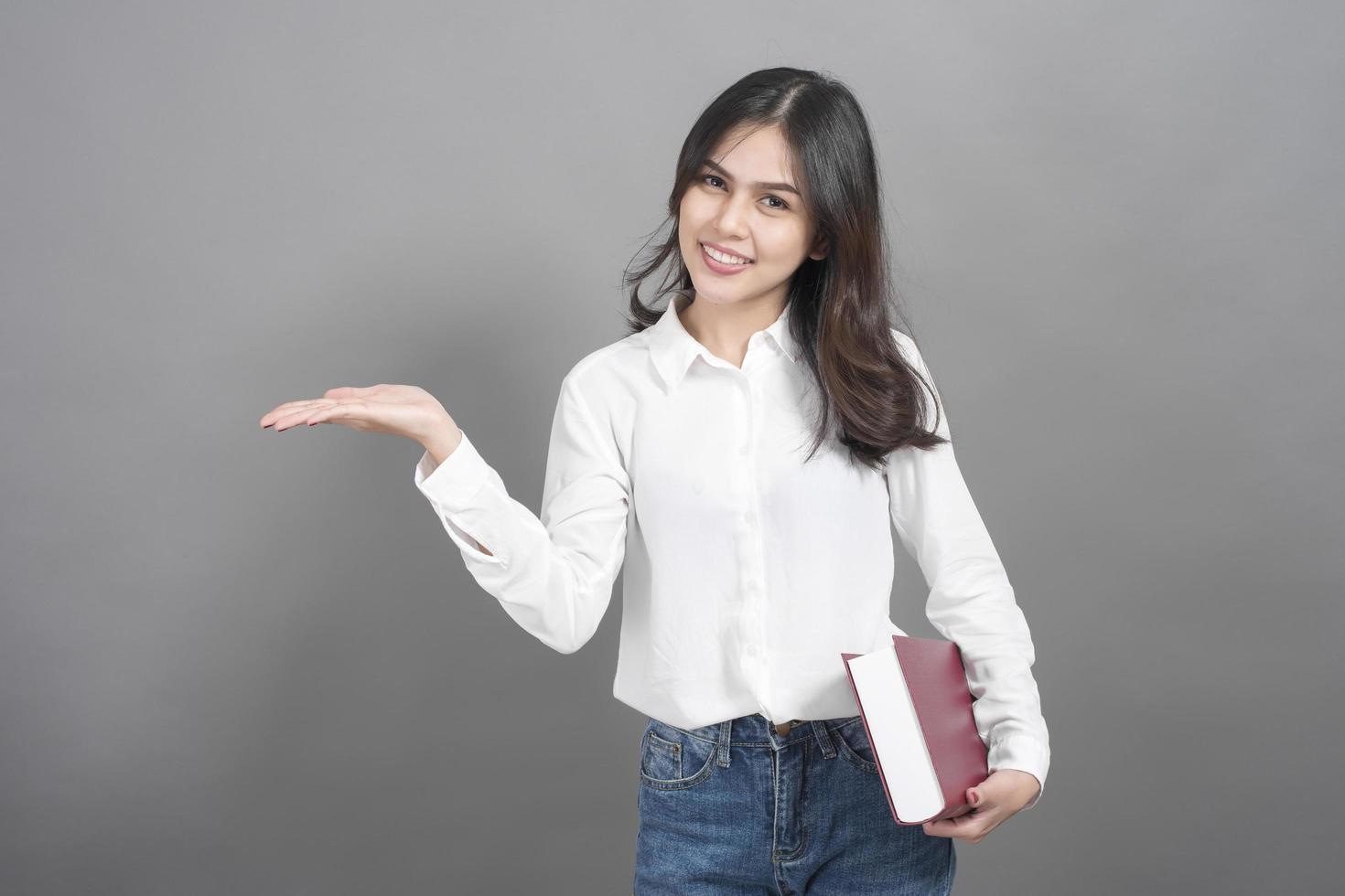 Portrait of woman University student holding book in studio grey background photo