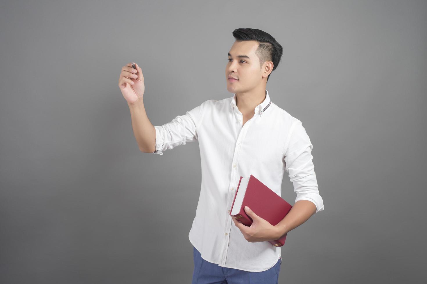 Portrait of man University student holding book in studio grey background photo