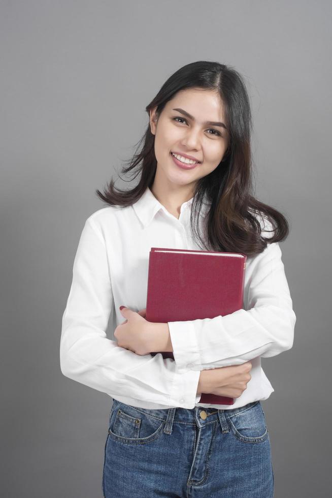 retrato, de, mujer, estudiante universitario, tenencia, libro, en, estudio, fondo gris foto