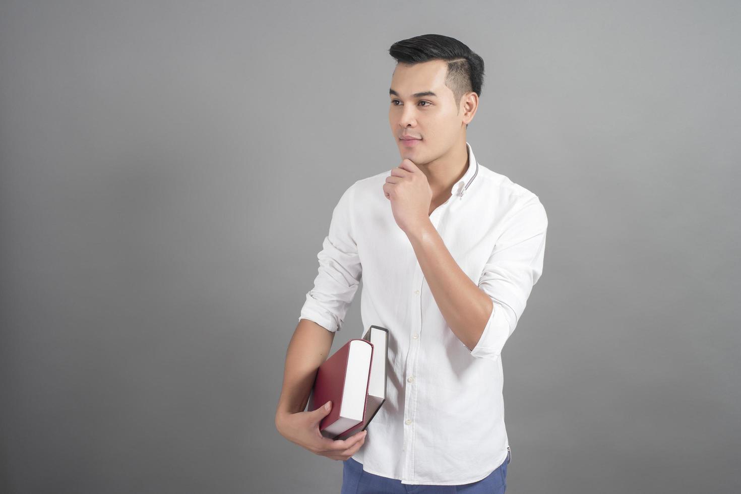 Portrait of man University student holding book in studio grey background photo