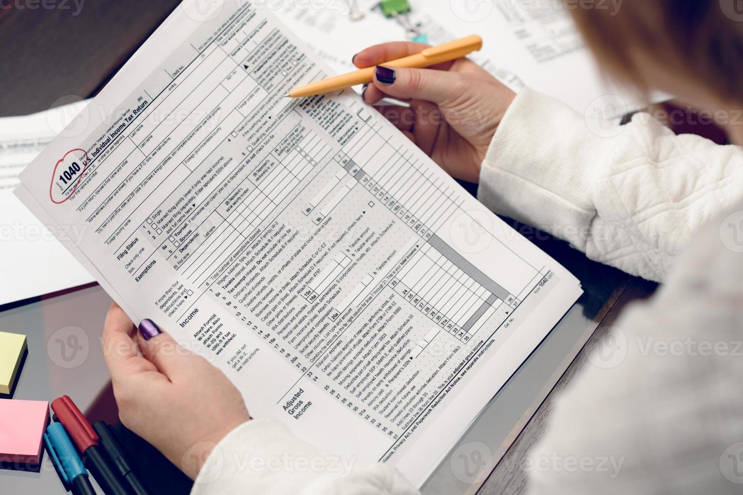 mujer llena el formulario de impuestos, trabajando con documentos fiscales. formulario 1040 formulario de declaración de impuestos sobre la renta de las personas físicas. formularios de impuestos de los estados unidos. formularios de impuestos estadounidenses en blanco. tiempo de impuestos. foto