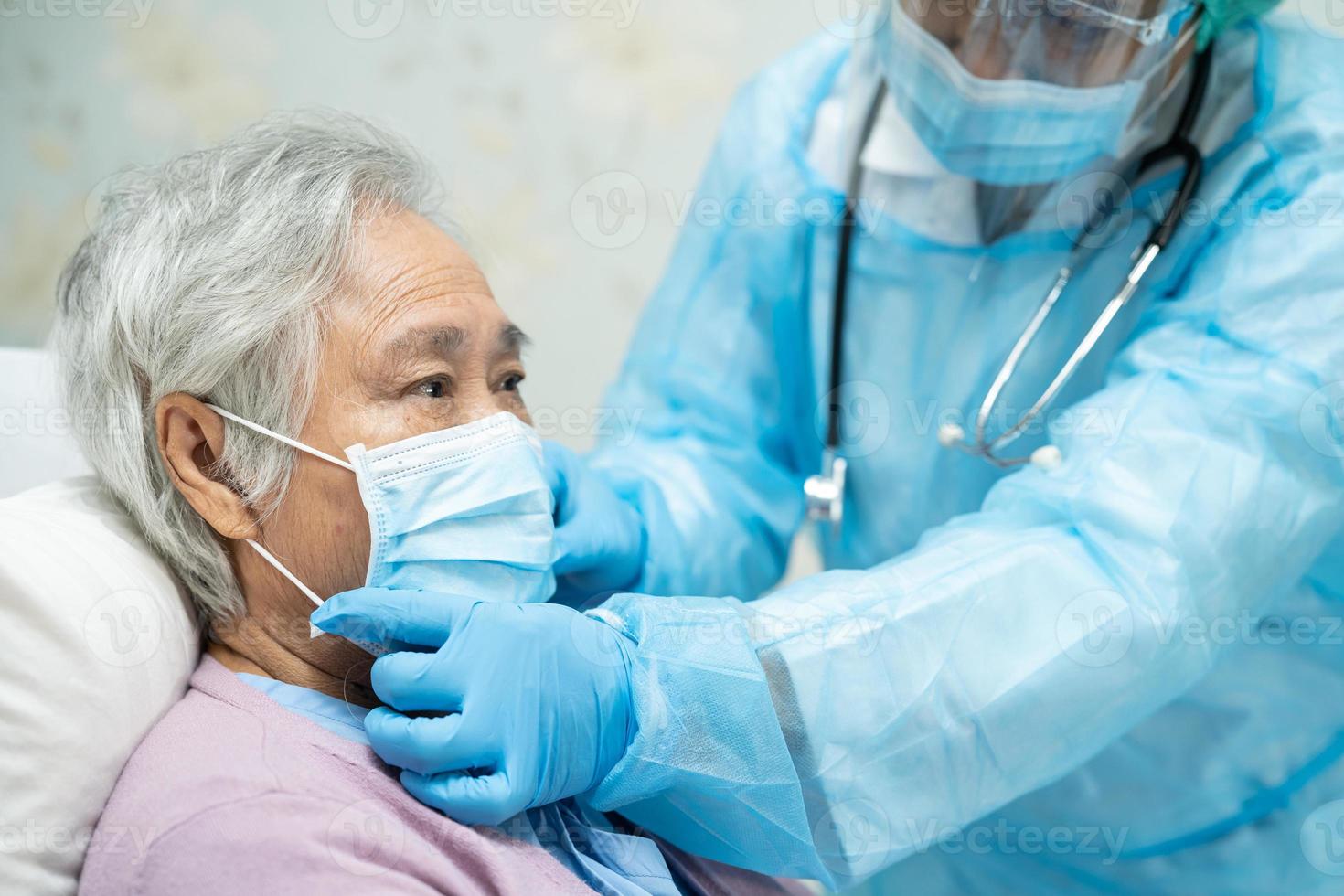 médico asiático con protector facial y traje de ppe nuevo normal para comprobar que el paciente protege la seguridad infección brote de coronavirus covid-19 en la sala de cuarentena del hospital de enfermería. foto