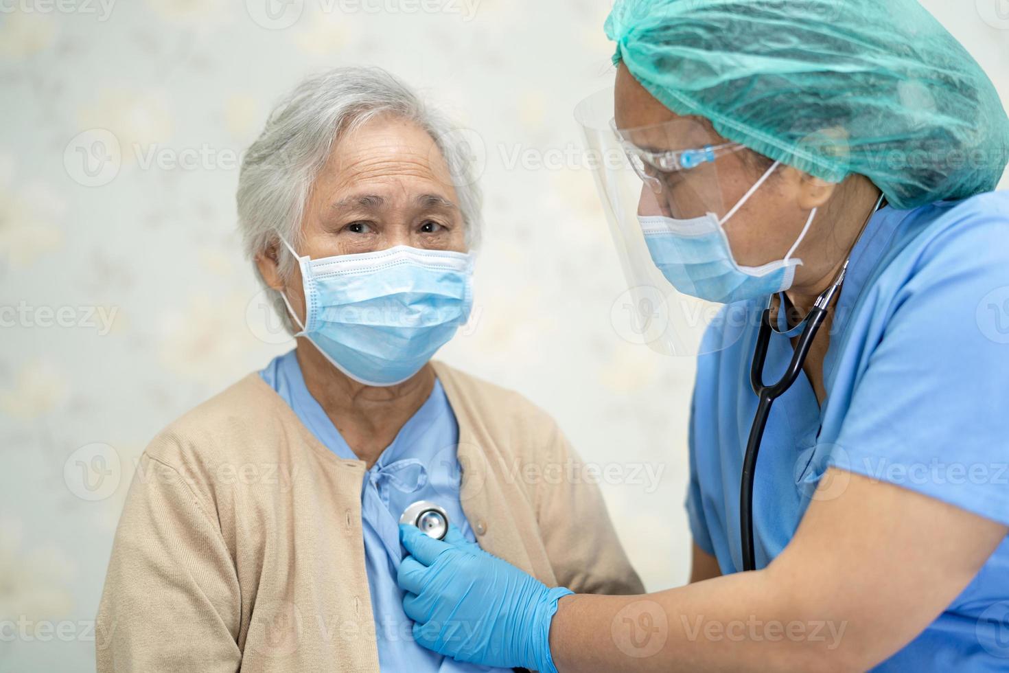 médico que usa estetoscopio para verificar que el paciente asiático mayor o anciano usa una mascarilla en el hospital para proteger la infección por el coronavirus covid-19. foto