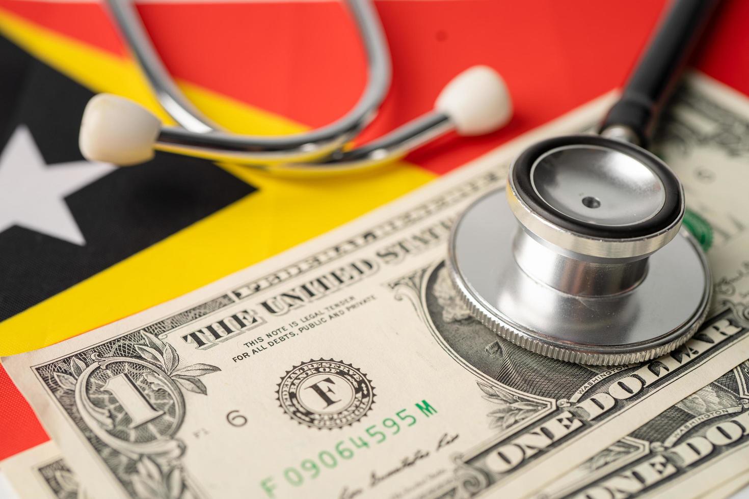 Black stethoscope with US dollar banknotes on East Timor flag background, Business and finance concept. photo