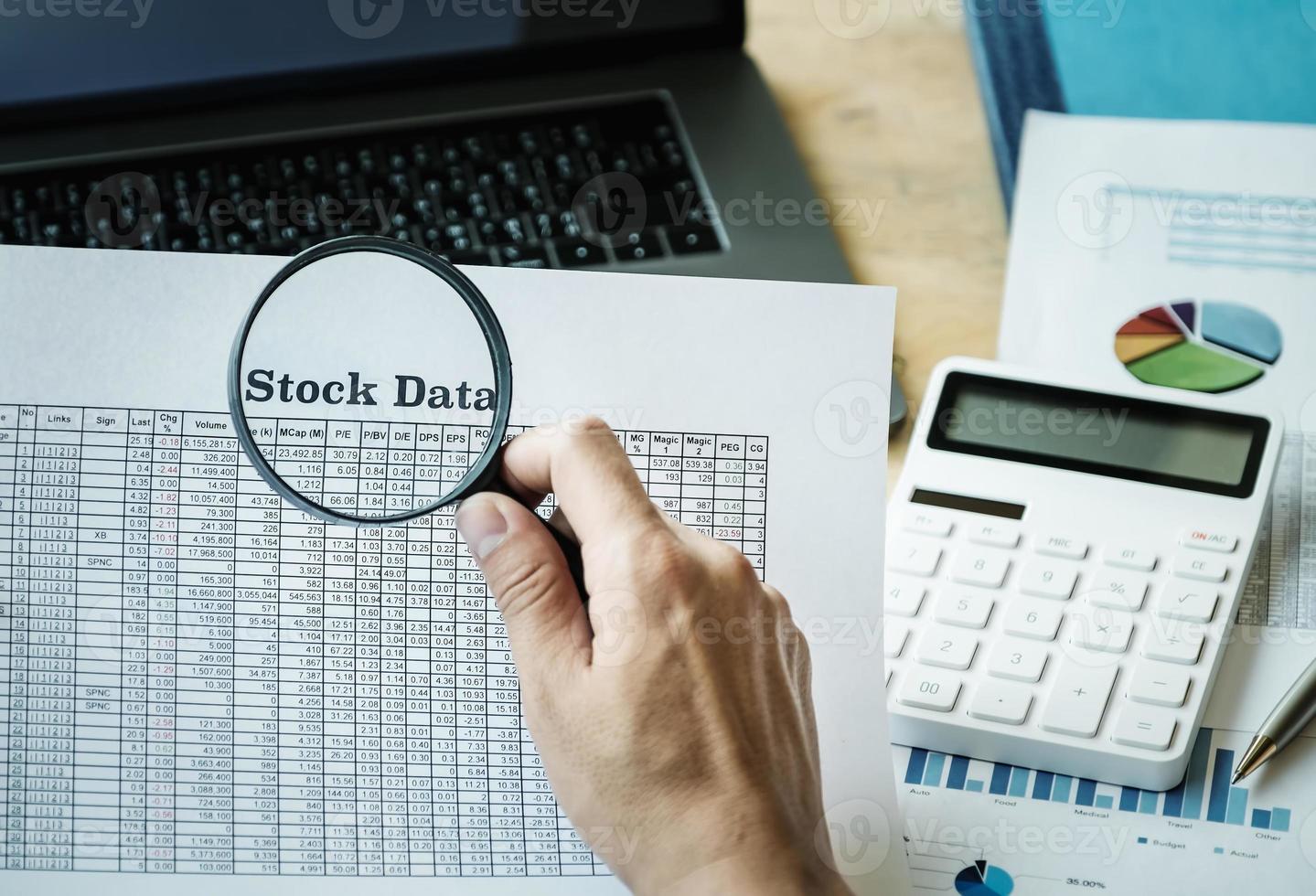 Businessman using magnifying to review balance sheet photo