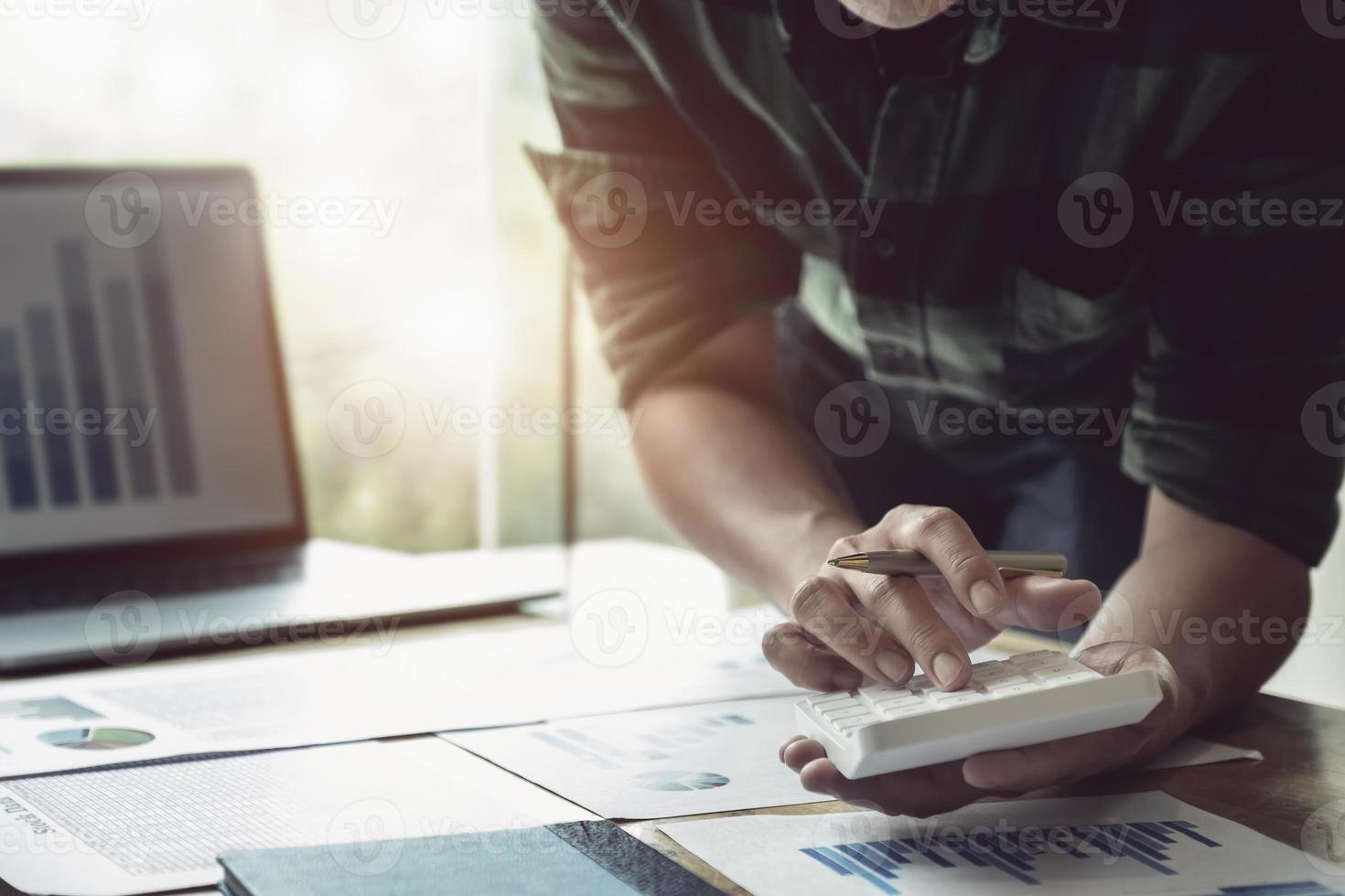 Businessman using calculator to review balance sheet photo