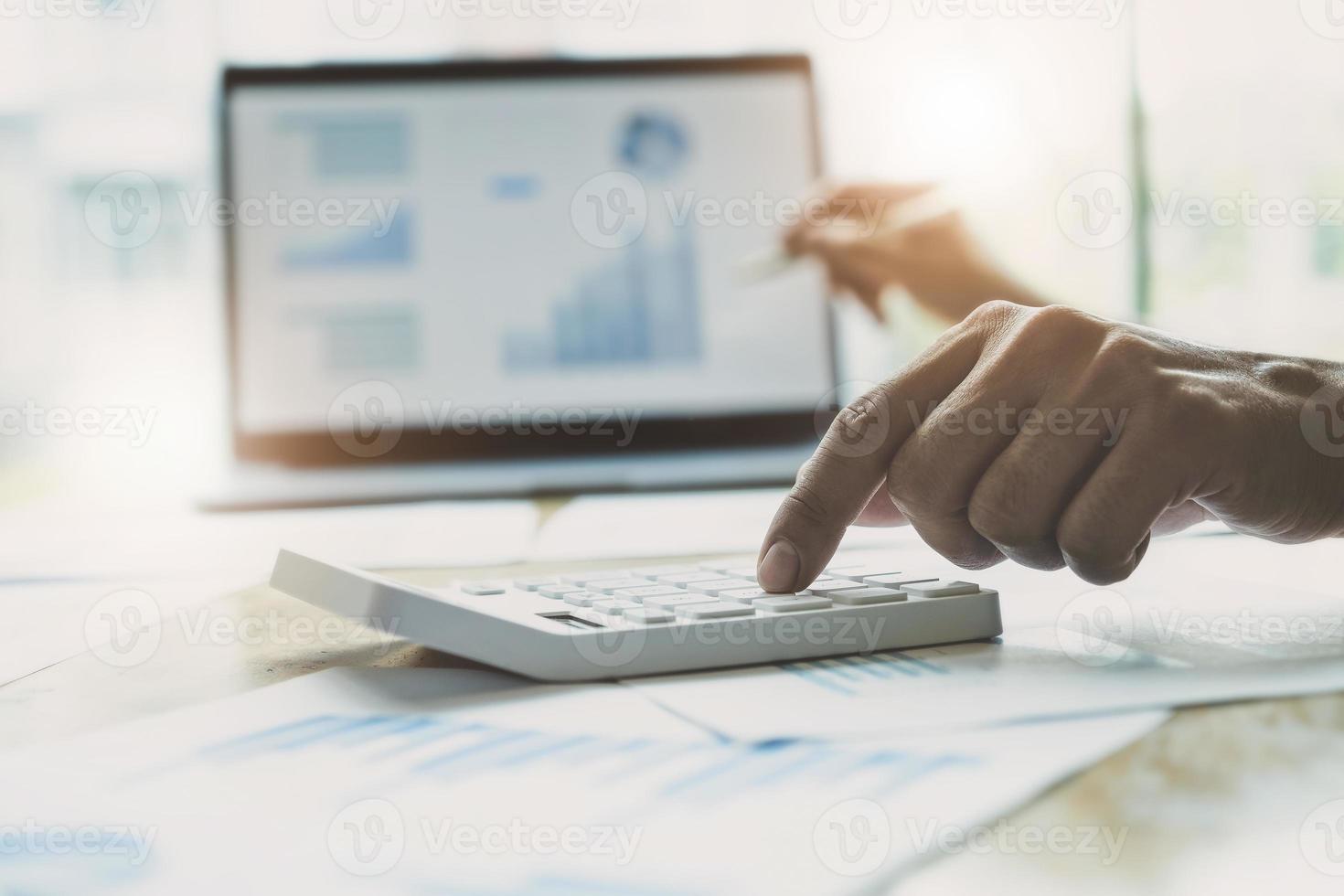 Businessman using calculator to review balance sheet photo