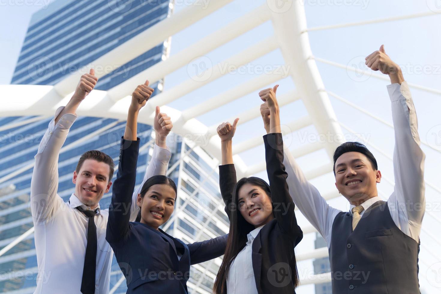 Cuatro ejecutivos seguidos, equipo empresarial de pie y vitoreando frente a la oficina moderna, concepto de liderazgo foto