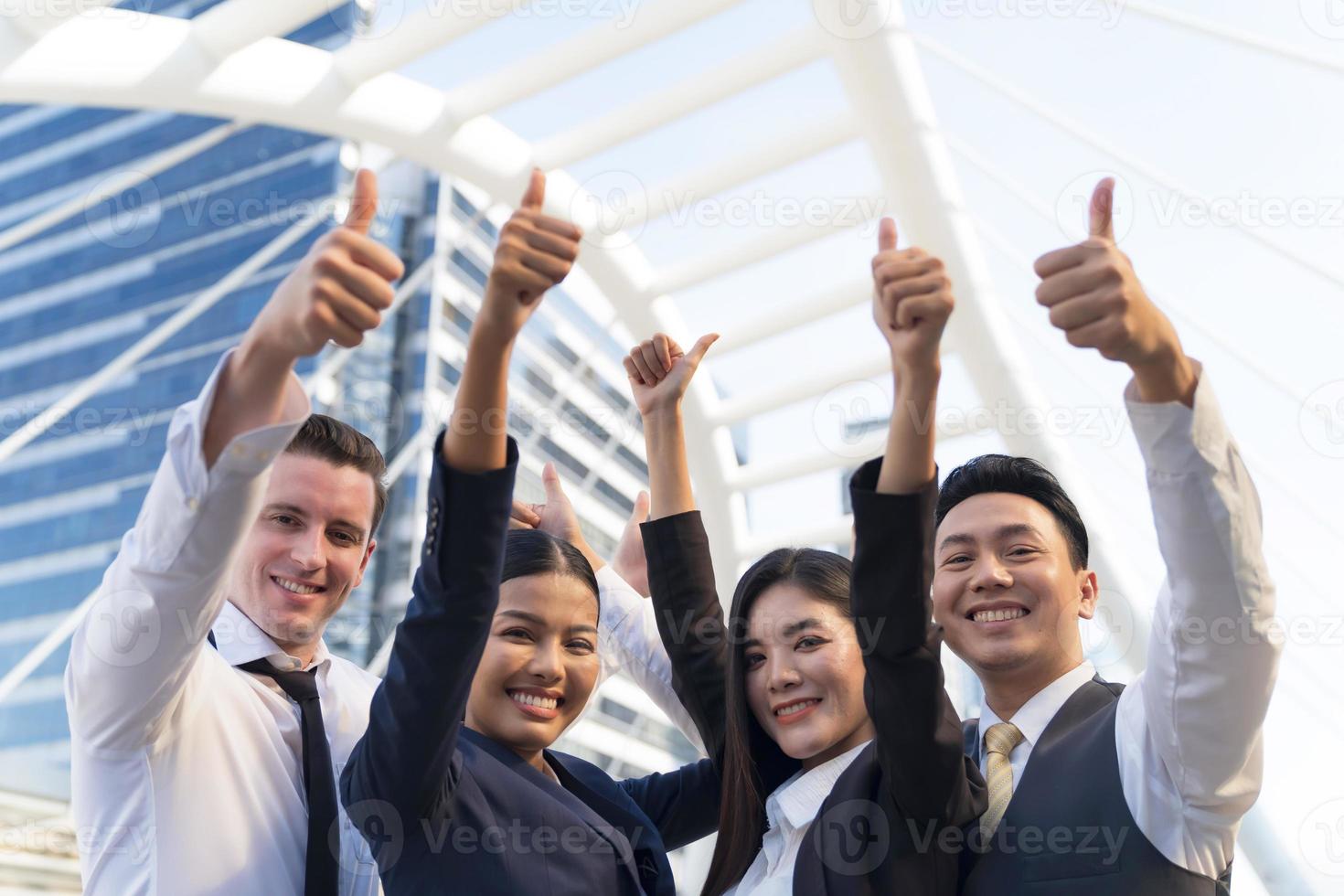 Cuatro ejecutivos seguidos, equipo empresarial de pie y vitoreando frente a la oficina moderna, concepto de liderazgo foto