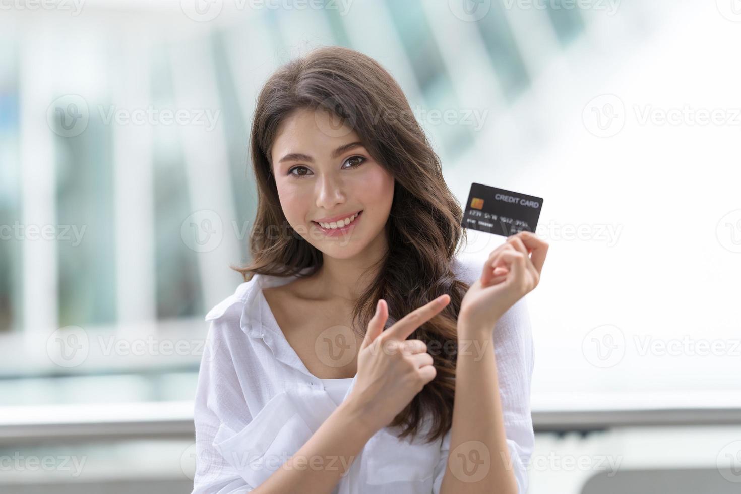 concepto de viernes negro, mujer con tarjeta de crédito y sonriendo cerca de la tienda foto
