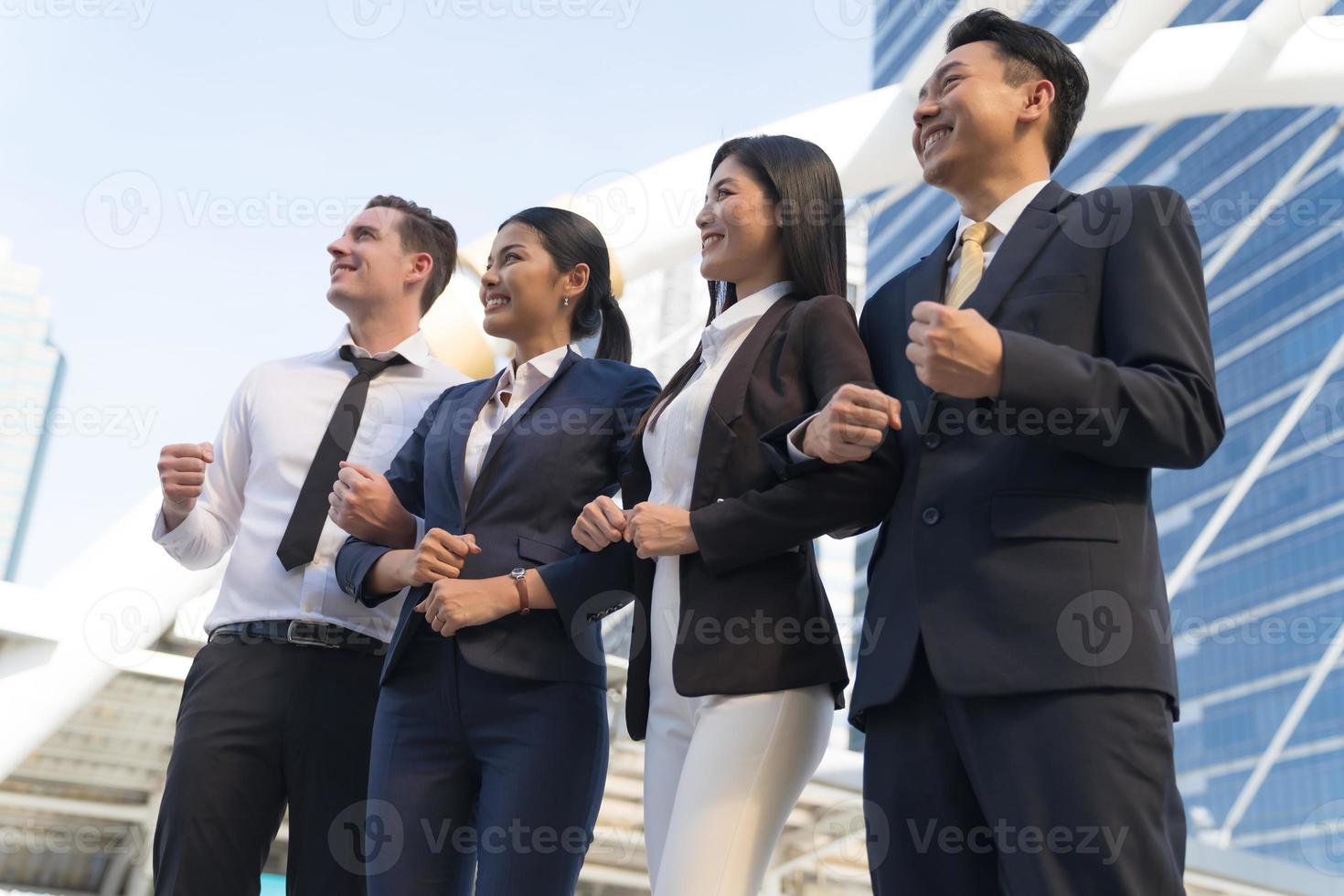 Cuatro ejecutivos seguidos, equipo empresarial de pie y vitoreando frente a la oficina moderna, concepto de liderazgo foto