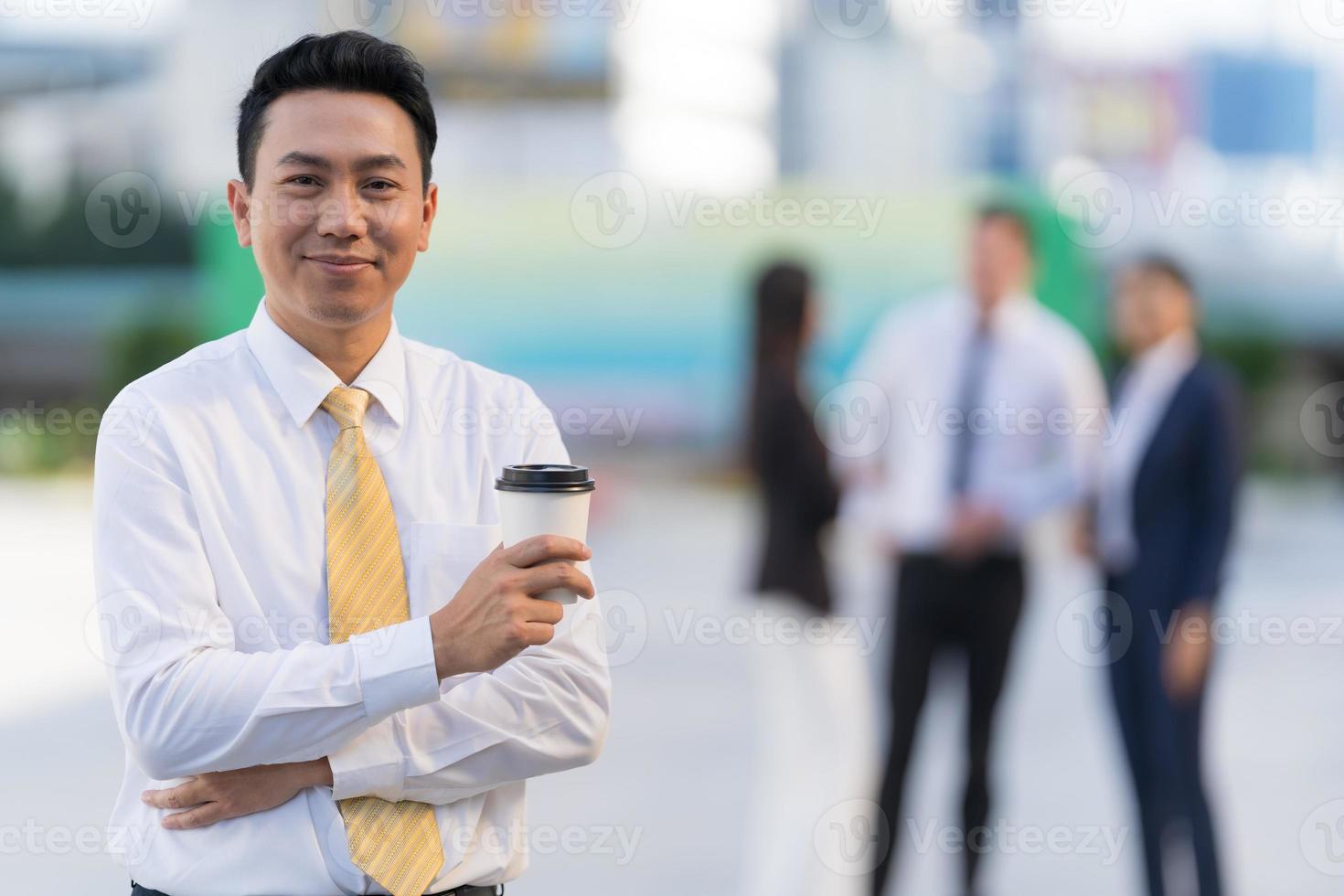 retrato, de, sonriente, hombre de negocios, tenencia, un, taza de café, mientras, posición foto