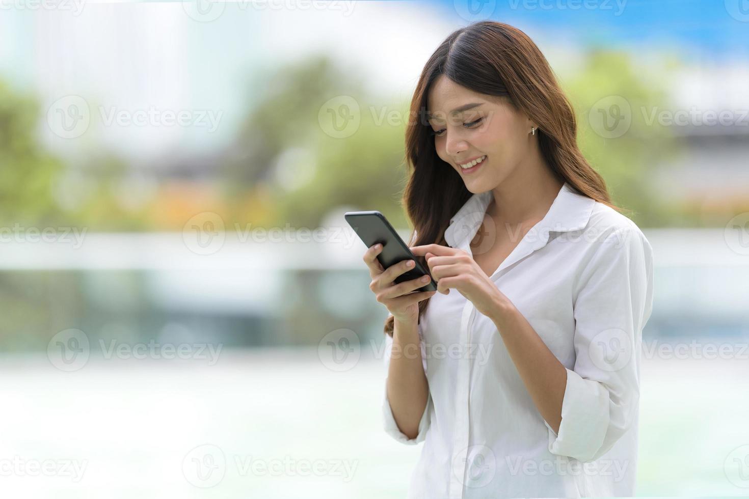 Outdoors portrait of Happy young woman using a phone photo